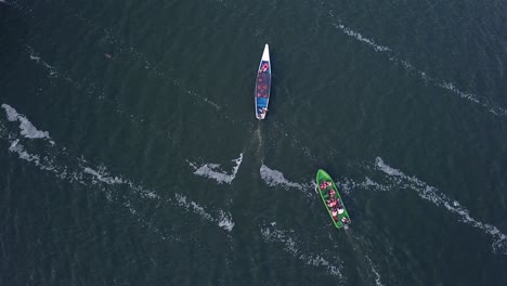 Drone-view-from-above-of-a-blue-boat-and-a-green-boat-sailing-together-on-a-river