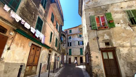 Person's-POV-Walking-In-The-Narrow-Street-Of-Ventimiglia-With-Clothes-Hanging-On-The-Buildings-To-Dry