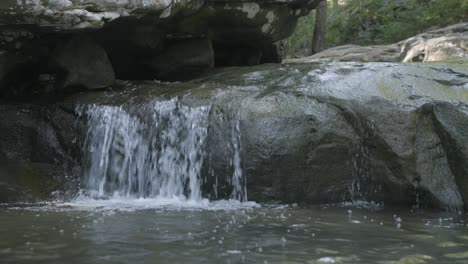 Close-up-footage-of-a-small-waterfall-coming-off-a-rock-in-a-stream