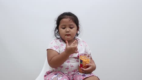 Adorable-Asian-little-girl-sitting-while-eating-snack