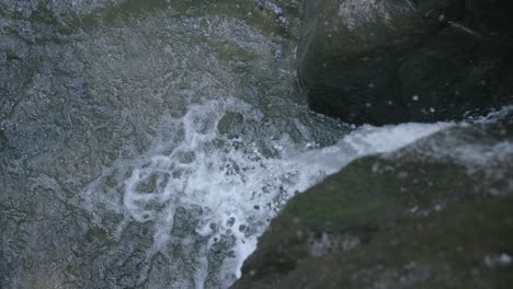 Slow-motion-footage-of-water-crashing-off-a-rock-and-falling-into-a-pool-of-water