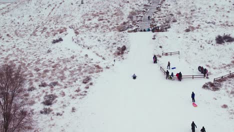 Aerial-shot-of-a-kid-sliding-down-a-steep-snow-covered-hill