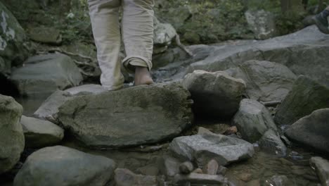 Bare-feet-of-a-teenager-walking-on-rocks-in-a-stream