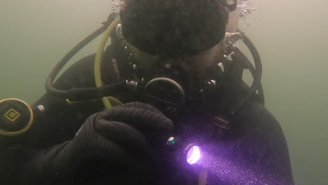 Scuba-Diver-shining-a-torch-searching-underwater-in-poor-visibility
