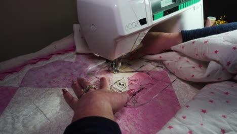 Using-a-plastic-template-fitted-on-a-sewing-machine-to-stitch-a-pattern-into-a-handmade-quilt---isolated