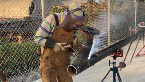 Static-shot-of-a-welder-working-on-a-large-piece-of-metal-pipe-himself