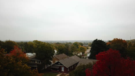 Absteigende-Luftaufnahme-über-Einem-Wohngebiet,-Die-Die-Leuchtenden-Herbstfarben-Der-Bäume-Enthüllt