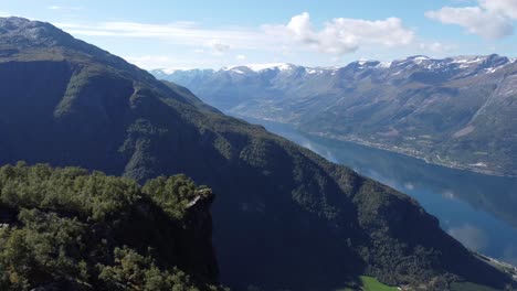 Nosi-viewpoint-and-special-mountain-tip-above-Lofthus-village-in-Hardanger-with-Sorfjorden-fjord-and-Folgefonna-glacier-in-background---Aerial-Norway