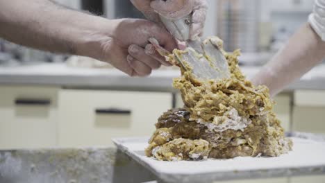Slow-motion-shot-of-a-dough-for-sweets-being-portioned-with-a-metal-spatula-by-a-baker-in-the-sweets-factory-in-medina-sidonia