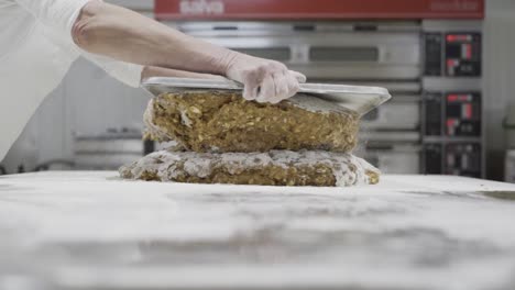 Slow-motion-panning-shot-of-a-dough-for-sweets-being-stacked-and-portioned-with-a-tablet-by-a-baker-in-a-sweets-factory-in-medina-sidonia