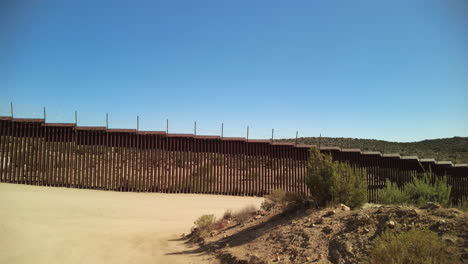 Border-fence-dividing-USA-and-Mexico-in-rural-California,-panning-shot
