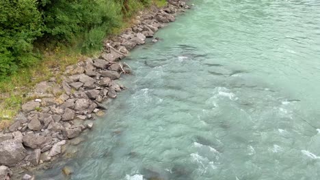 Alpine-river-showing-shoreline-with-blue-green-water