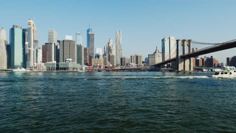 Panning-Panoramic-View-of-Manhattan-Skyline,-Brooklyn-Bridge-and-Hudson-River-from-Brooklyn-Bridge-Park-on-Sunny-Day