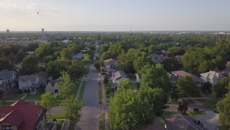 Drone-moving-backward-and-captures-the-road-of-the-suburbs-with-multiple-residence-on-the-side-and-green-trees