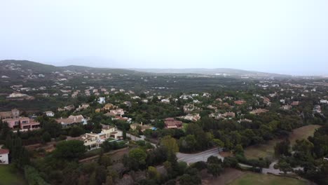 Drone-flying-over-small-suburban-town-in-hills-and-countryside,-Spain