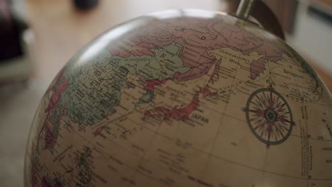 Close-up-shot-of-a-hand-spinning-a-vintage-globe-and-landing-on-East-Asia