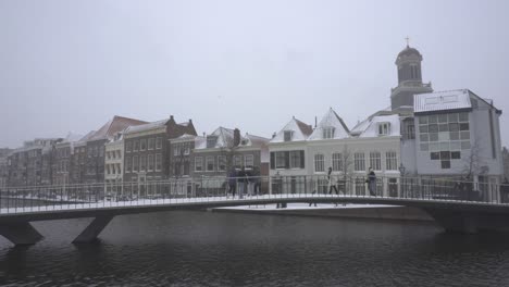 People-crossing-bridge-in-snowy-winter,-historic-town-Leiden,-Netherlands