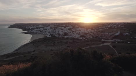 Crane-up-Reveal-of-Sun-Setting-over-Praia-da-Luz,-Algarve---Aerial