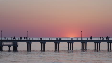 Zeitraffer-Des-Sonnenuntergangs-In-Der-Ostsee-Mit-Menschen,-Die-Auf-Dem-Pier-Von-Palanga-Spazieren-Gehen