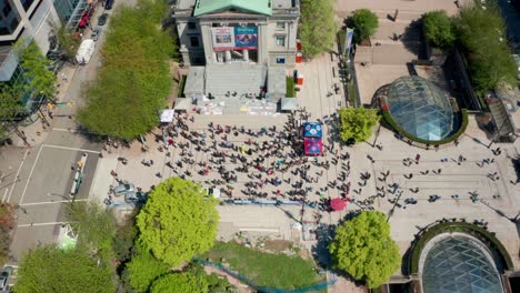 People-gather-to-demonstrate-in-a-public-square,-aerial-drone-view