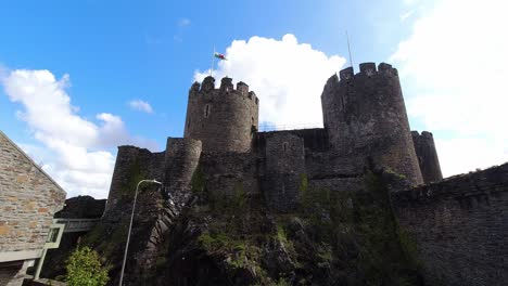 Fast-moving-clouds-above-medieval-Conwy-castle-battlements-turret-towers-looking-up