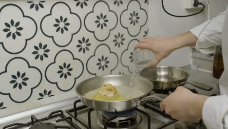 Küchenchef-Fügt-Wasser-In-Die-Pfanne-Mit-Gerollter-Lasagne-Hinzu
