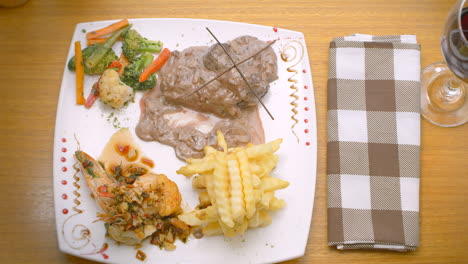 Meat-in-sauce,-prawns,-French-fries-and-steamed-vegetables,-Mediterranean