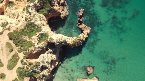 Golden-cliff-Escarpment-opposing-turquoise-sea-in-Lagos,-Algarve,-Portugal---Aerial-Bird's-eye-view-fly-over-shot