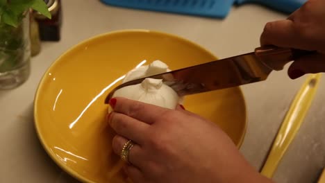 Slicing-a-fresh-baby-mozzarella-ball-in-half-to-use-in-a-salad---slow-motion-isolated
