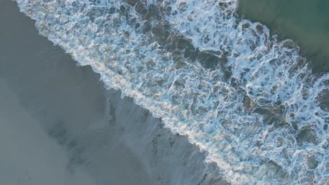 UAE:-Aerial-view-of-waves-breaks-on-the-beach,-Bird's-eye-view-of-ocean-waves-crashing-and-foaming-against-the-empty-shore,-rough-sea-view