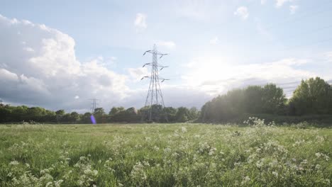 rising-shot-of-power-lines-electric-pylon-on-a-sunny-day-green-field