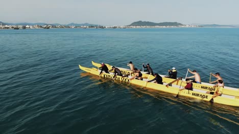 Aerial-tracking-shot-of-kayaker-group-kayaking-in-double-canoe-on-Atlantic-ocean-in-Santa-Catarina,-Brazil-during-sunny-day