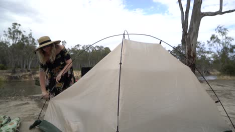 Blonde-woman-packing-up-tent-outdoor-camping-in-Australia