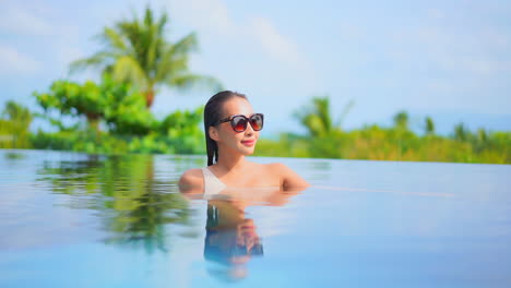 Chest-high-in-the-relaxing-pool-water-a-young-woman-looks-around-at-the-scenery
