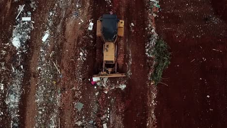 A-bulldozer-pushes-trash-at-a-landfill-site---aerial-straight-down-view