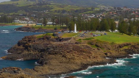 Vehicles-Park-Beside-The-Kiama-Lighthouse-With-Townscape-On-The-Background