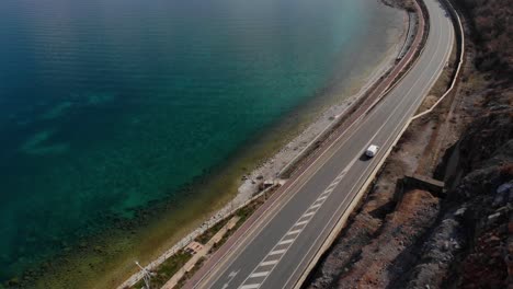 Road-alongside-beautiful-lake-shore-with-calm-crystal-water,-travel-concept
