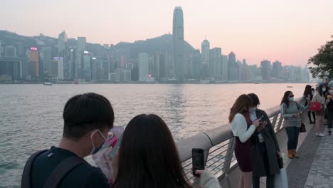 Ein-Paar-Macht-Ein-Selfie,-Während-Es-Eine-Rosenboutique-Am-Ufer-Des-Victoria-Harbour-Hält,-Um-Den-Blick-Auf-Die-Skyline-Der-Insel-Hong-Kong-Zu-Genießen,-Während-Der-Sonnenuntergang-Einsetzt