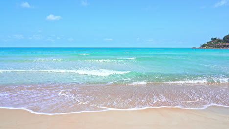 Static-shot-of-calm-ocean-waves-reaching-shore-of-a-white-sand-beach-during-bright-sunny-day-on-a-tropical-island