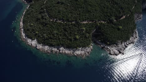 Drone-video-in-Dubrovnik-between-the-island-of-Lokrum-and-the-Croatian-coast-at-sunset-with-yacht-and-speedboat-in-the-sea