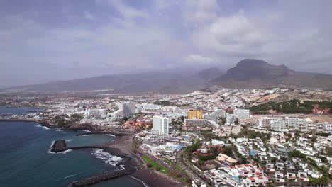 Aerial-tilt-up-reveal-of-a-touristic-resort-city-on-Tenerife-coastline