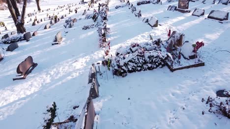 Gravestones-covered-in-pure-white-snow,-low-altitude-drone-fly-over