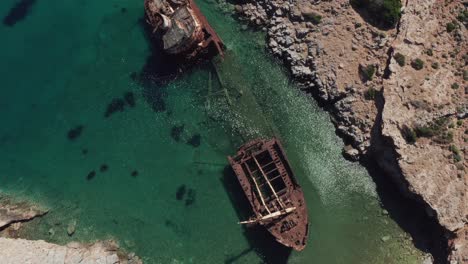A-top-view-by-drone-of-the-abandoned-boat-in-Liverio-bay-near-Kalotaritissa-village,-Cyclades-islands,-Greece