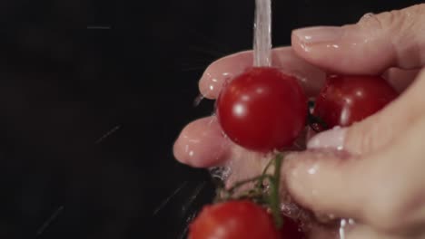 hands-gently-rinsing-the-ripe-red-cherry-tomatoes-one-by-one-under-the-water-tap---close-up-shot