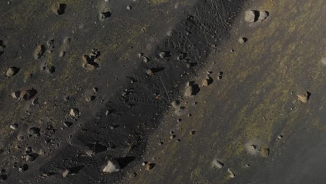 Vista-De-Pájaro-Del-Suelo-Con-Rocas-Y-Arena-Negra-Disparada-Por-Un-Dron-En-Islandia