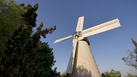 Approaching-the-old-traditional-stone-windmill-Montefiore-Windmill-in-the-Jerusalem-countryside,-seen-from-below,-then-going-backwards