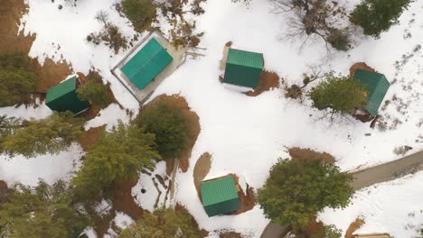 A-frame-cabins-in-the-snowy-mountains-provide-warmth-and-shelter-from-the-winter---straight-down-aerial-view