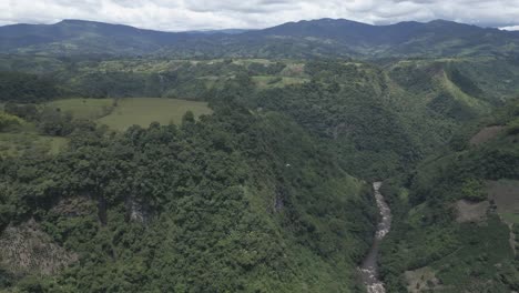 Aerial-Drone-Pan-Above-Magdalena-River,-Colombian-Andean-Valley,-Cloudy-Morning-Flying-The-Green-Deep-Forest-Vegetation
