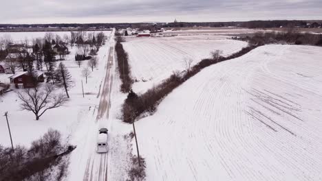 Vehicle-towing-white-horse-trailer-on-icy-winter-road,-aerial-drone-shot