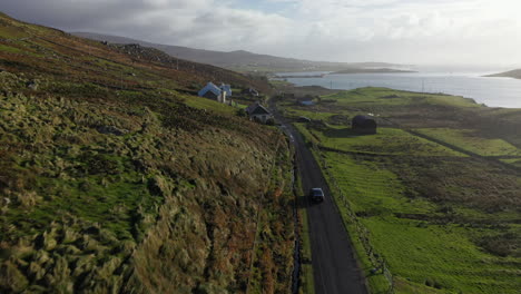 Cinematic-following-drone-shot-of-a-car-driving-through-the-White-Cliffs-of-Ashleam,-Ireland